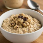 Creamy high-protein cookie dough oats topped with cookie dough chunks and mini chocolate chips in a rustic bowl