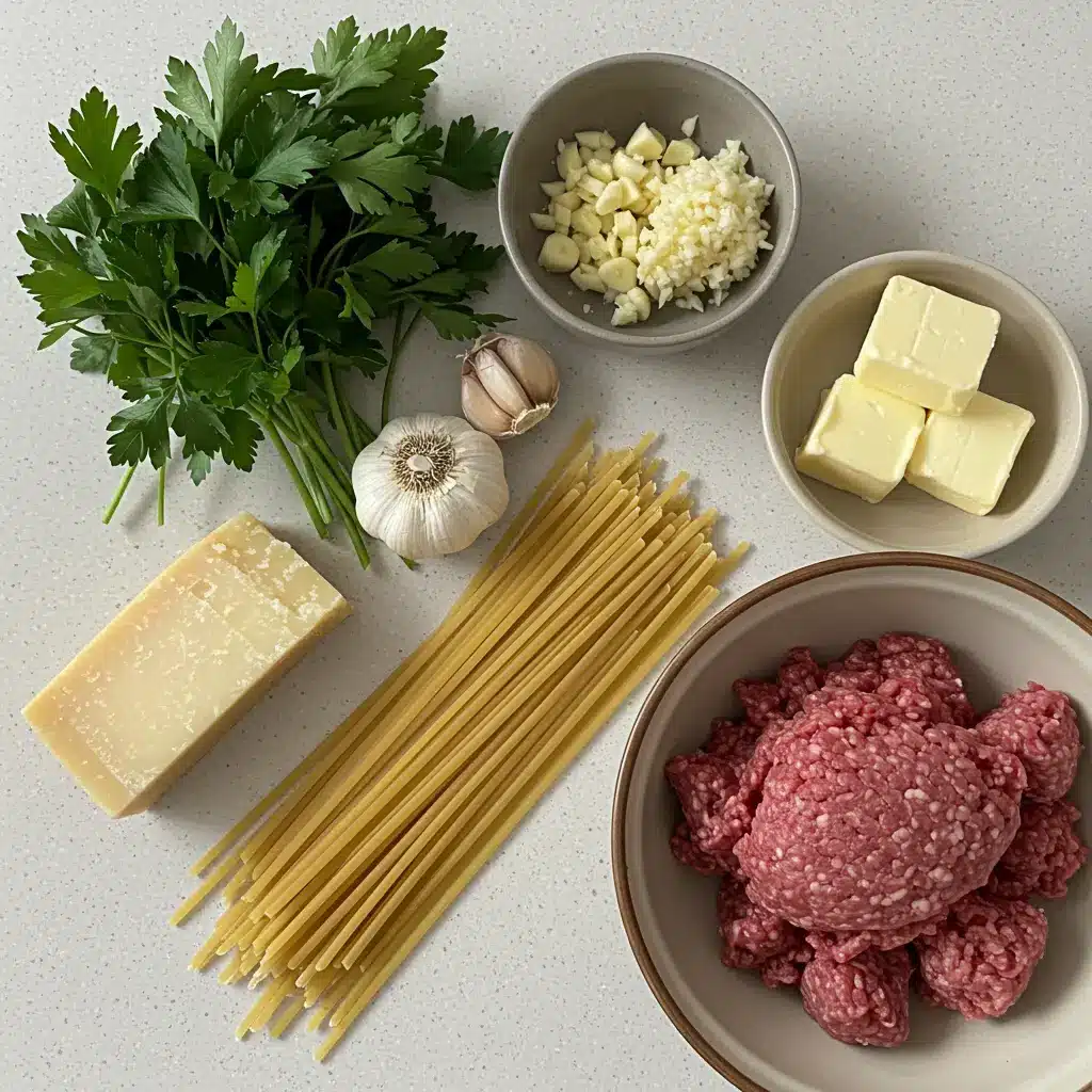 Fresh ingredients for Easy Garlic Butter Meatballs with Creamy Linguine, including ground beef, linguine, butter, garlic, and Parmesan, laid out on a kitchen counter.