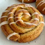Close-up of golden-brown Peach Pie Cruffins showing flaky layers and glossy peach filling on a light plate, perfect for a homemade dessert recipe.