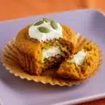 A close-up shot of a perfect pumpkin cream cheese muffins with a bite taken out, showing the moist inside and creamy filling.